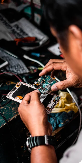 Technician holding a smartphone motherboard during component-level phone repair.