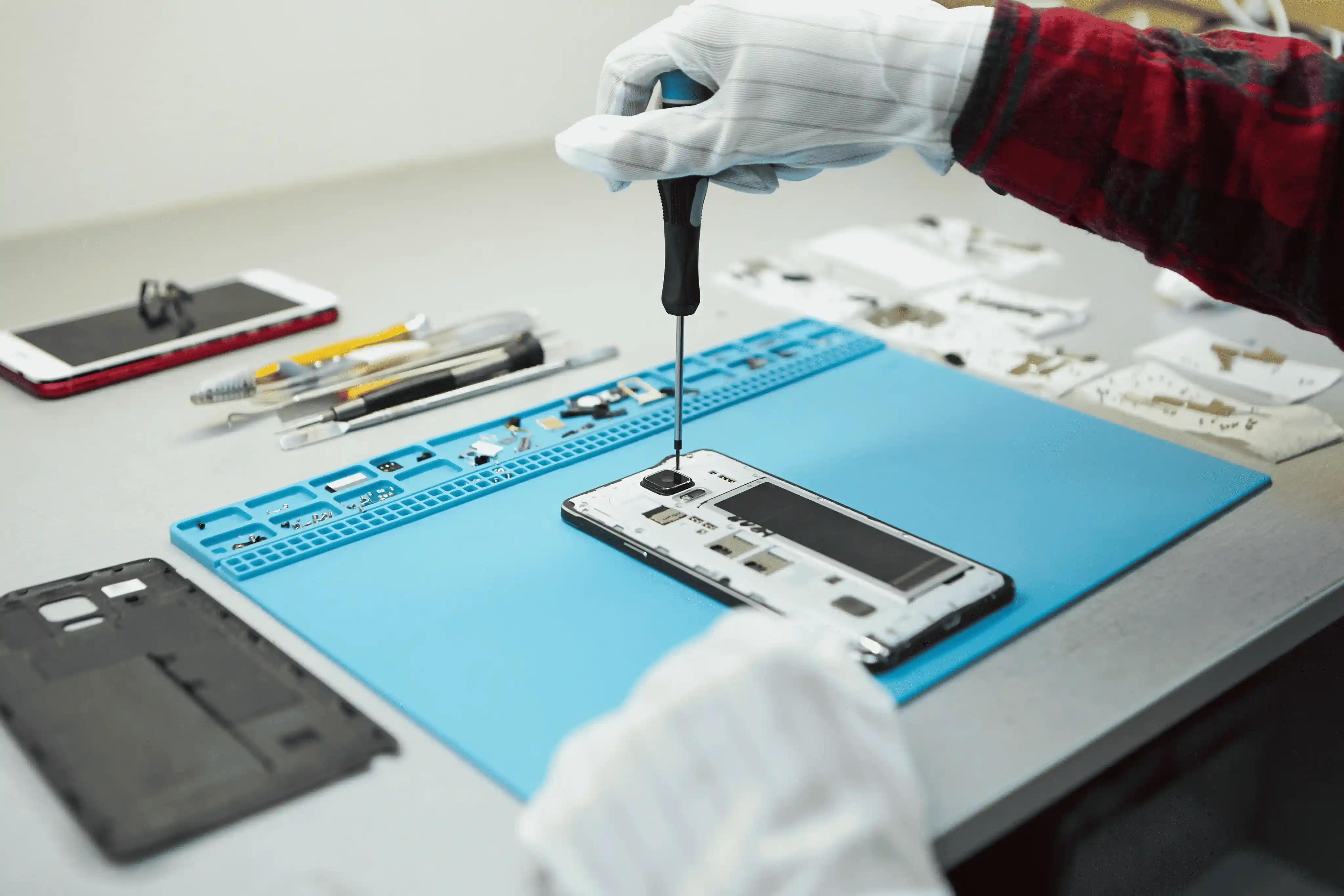 Professional technician repairing a disassembled smartphone with precision tools